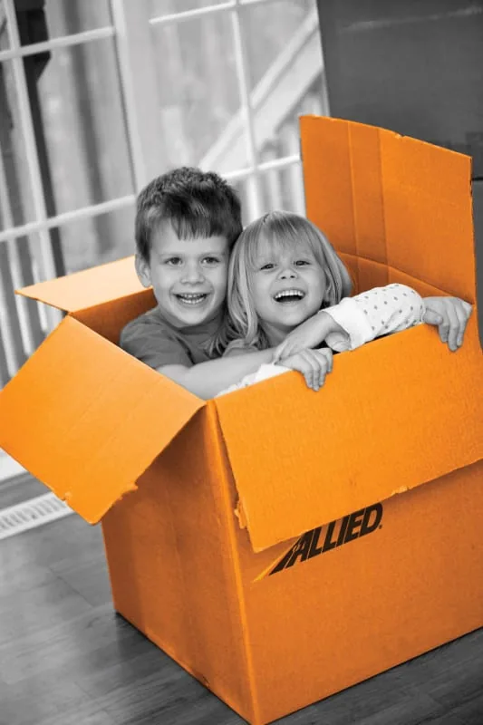 Two children playing inside an Allied moving box on moving day