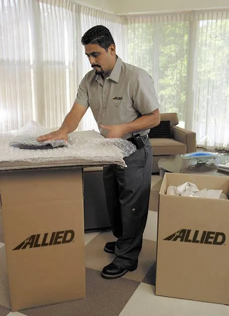 Allied packer wrapping fragile items into a moving carton
